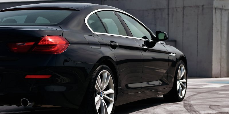 A black car is parked on a concrete surface.