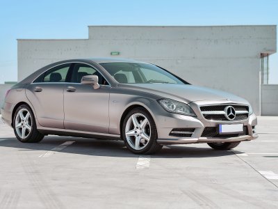 A silver car parked in a parking lot, showcasing its alloy wheels and sleek design under a clear sky.